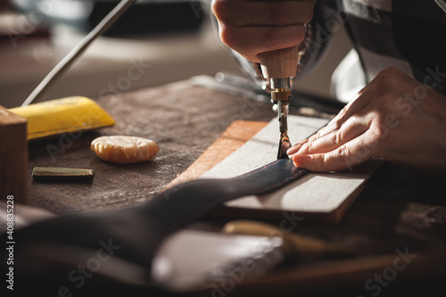 Leather handbag craftsman at work in a vintage workshop. Small business concept photo