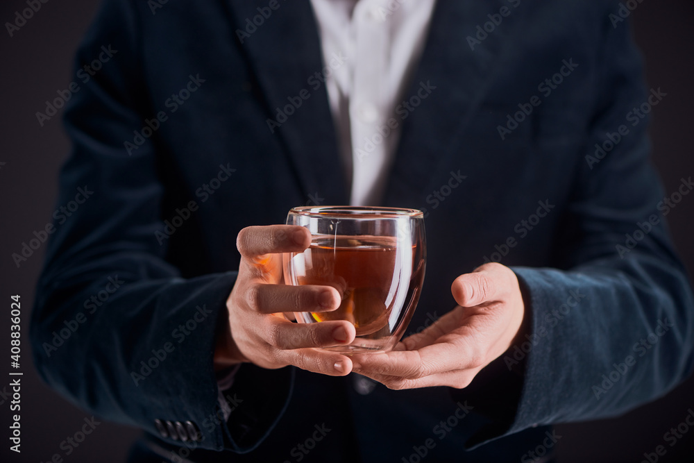 Midsection portrait of a man in a blazer holding a glass cup of tea Midsection portrait of a man in a blazer holding a glass cup of tea
