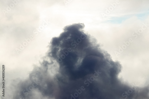 Dark formidable cloud in the bright sky, thick smoke in the sky