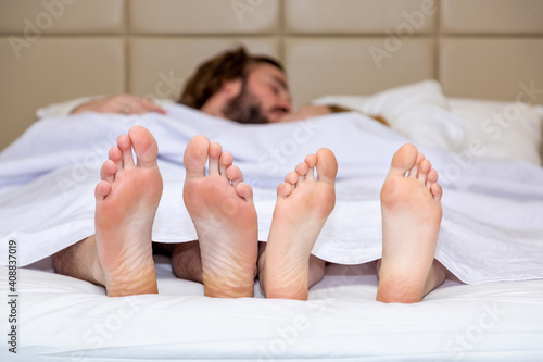 Front view of naked feet. Young couple in love kissing and relaxing in bed. Concept about lifestyle and people.