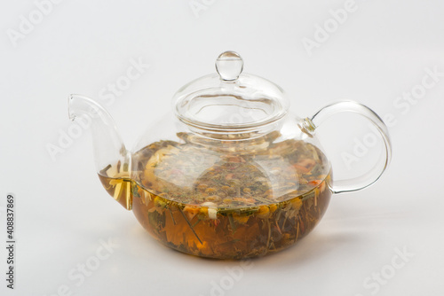 A glass teapot with steeped herbal tea on white background