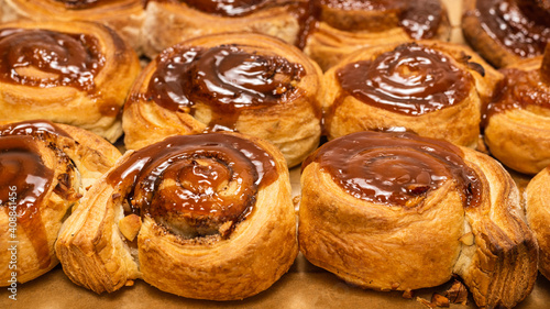 Homemade cinnamon buns with spices and caramel on parchment paper.