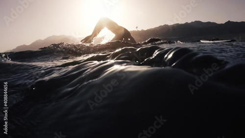 Athletic young man swimming at sea. Professional triathlon swimmer in ocean water. Young man athlete practicing at open water