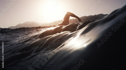 Athletic young man swimming at sea. Professional triathlon swimmer in ocean water. Young man athlete practicing at open water