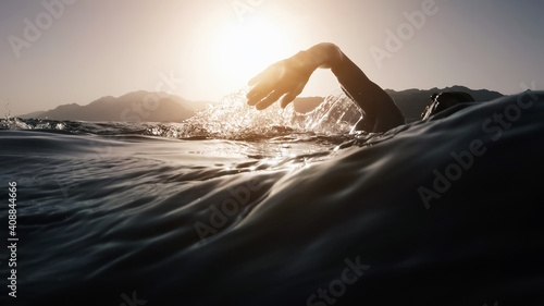 Athletic young man swimming at sea. Professional triathlon swimmer in ocean water. Young man athlete practicing at open water