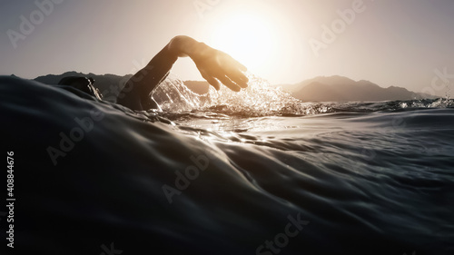 Athletic young man swimming at sea. Professional triathlon swimmer in ocean water. Young man athlete practicing at open water photo