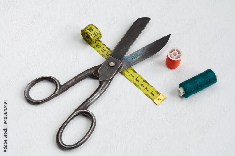 tailor scissors, spools of thread and a yellow centimeter on white background tailor scissors, spools of thread and a yellow centimeter on white background