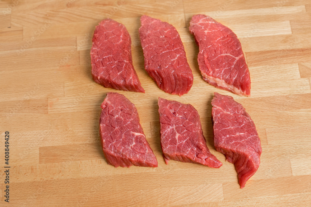 Six portions of beef meat are iced on a cutting board. top