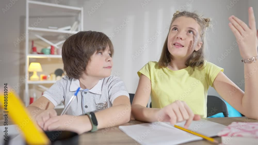 Confident Caucasian schoolgirl raising hand and answering question as schoolboy admiring classmate. Portrait of intelligent genius student studying at school in classroom. Education and intelligence. Confident Caucasian schoolgirl raising hand and answering question as schoolboy admiring classmate. Portrait of intelligent genius student studying at school in classroom. Education and intelligence.