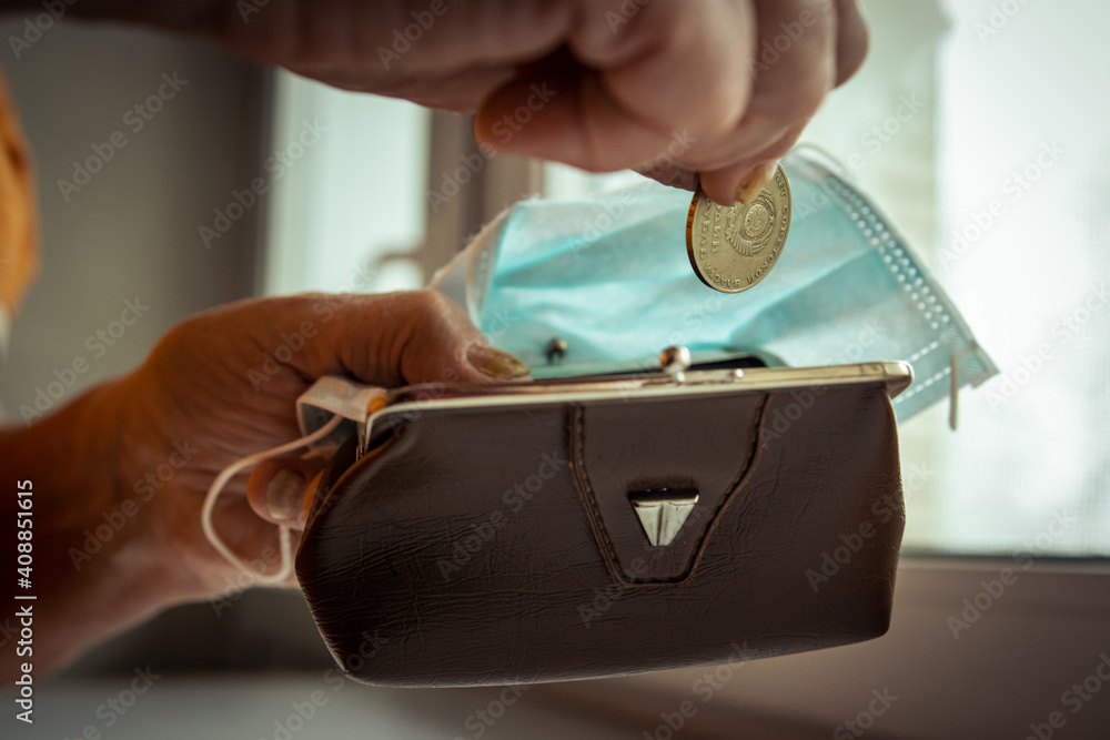 Obraz premium an elderly man puts a coin in his wallet. wallet and mask in hands. coin with the inscription one ruble of the USSR.