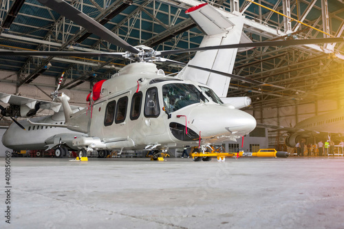 Passenger helicopter and airplanes in the hangar. Rotorcraft and aircrafts under maintenance. Checking mechanical systems for flight operations