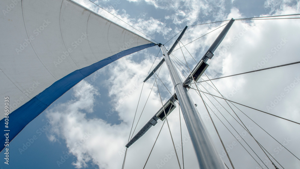 Mast and sail filled with wind against the sky Mast and sail filled with wind against the sky