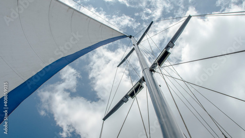 Mast and sail filled with wind against the sky