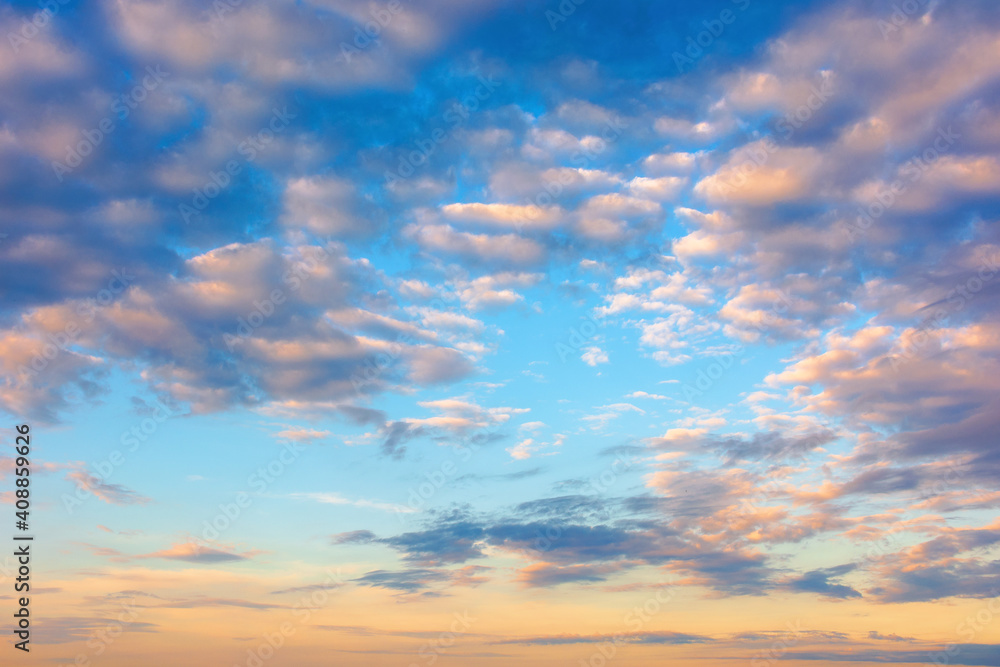 cloudscape in summer at sunrise. clouds on the blue sky in yellow and pink morning light. idyllic weather condition, picturesque scenery