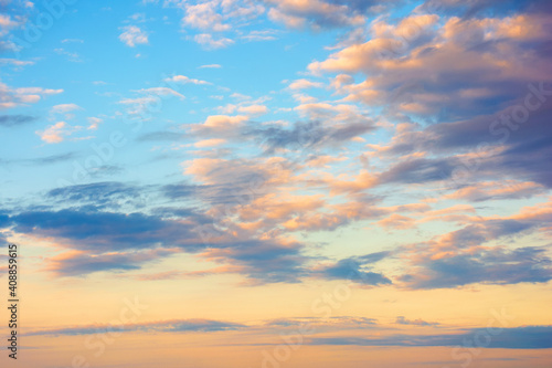 cloudscape in summer at sunrise. clouds on the blue sky in yellow and pink morning light. idyllic weather condition, picturesque scenery © Pellinni
