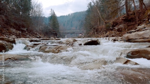 Waterfall in the Winter. Rapid Flow of Water from a Mountain Creek and Stone Rapids with Snow. The river Prut in Ukrainian Carpathians in Yaremche city.Melting ice and snow on the river in the forest.