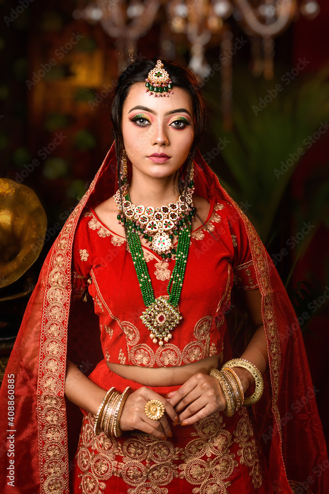 Magnificent young Indian bride in luxurious bridal costume with makeup and heavy jewellery with classic vintage interior in studio lighting. Wedding Lifestyle and Fashion