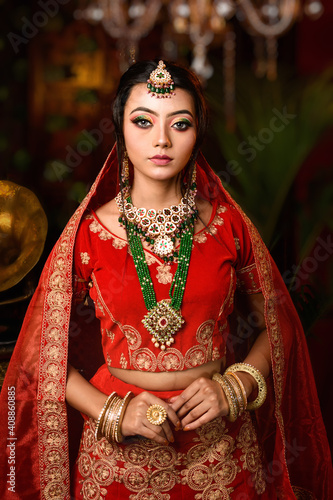 Magnificent young Indian bride in luxurious bridal costume with makeup and heavy jewellery with classic vintage interior in studio lighting. Wedding Lifestyle and Fashion