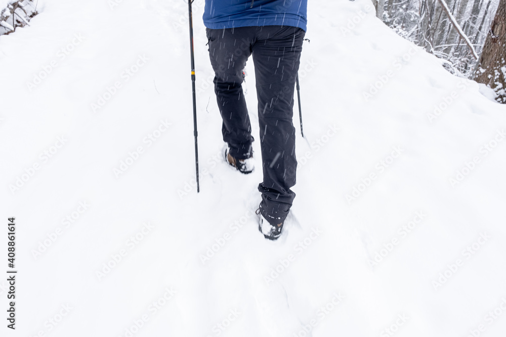 Rear view of Man walking through the deep snow on a winter day, motion blur defocus
