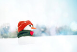 Little cute snowman in a orange hat and a green scarf with red heart in the snow, close-up. Valentines day card with a snowman