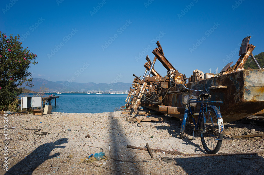 Old bicycle is leaning against aged large rusty metal structure for transporting boats in harbour under clear blue sky on mediterranean seaside in Fethiye, Turkey Old bicycle is leaning against aged large rusty metal structure for transporting boats in harbour under clear blue sky on mediterranean seaside in Fethiye, Turkey