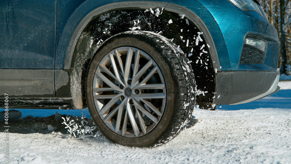 CLOSE UP: Powerful SUV's wheels spin in place and spew up pieces of white snow.