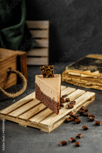 Still life of chestnut cake with chocolate mousse on a dark gray table with chocolate pieces.