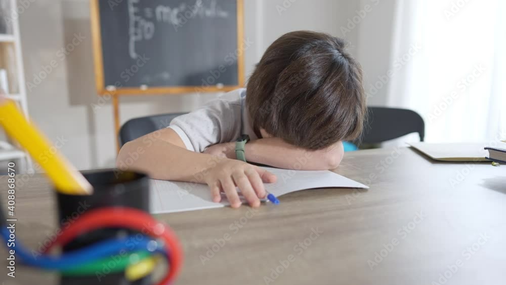 Brunette Caucasian schoolboy crying at desk in classroom. Portrait of upset overwhelmed boy sitting in school indoors. Education problems and sadness concept. Brunette Caucasian schoolboy crying at desk in classroom. Portrait of upset overwhelmed boy sitting in school indoors. Education problems and sadness concept.