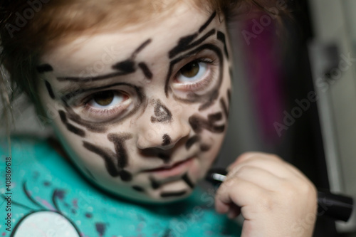 The little girl painted her face with crayons.-Children's mischief photo