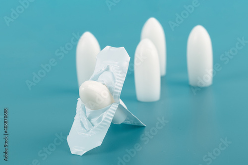 Medical suppository on a blue background.White rectal and vaginal unpacked candles.Soft focus.Сoncept of treatment of female diseases,hemorrhoids,cracks,anti-inflammatory,from temperature.