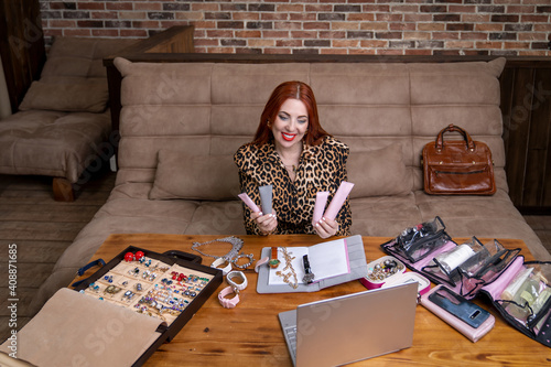 a young woman with a snow-white smile sits on a sofa and sells cosmetics online communicating with a customer via a laptop via video link