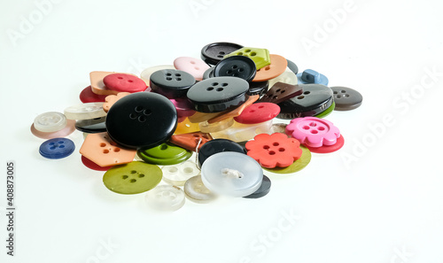 A close up of a heap of colorful buttons isolated on a plain white background