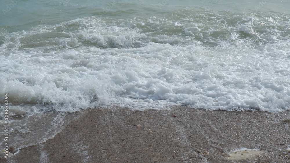 Mediterranean rocky beach with wavy sea in a cloudy morning