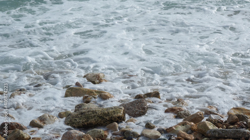 Mediterranean rocky beach with wavy sea in a cloudy morning