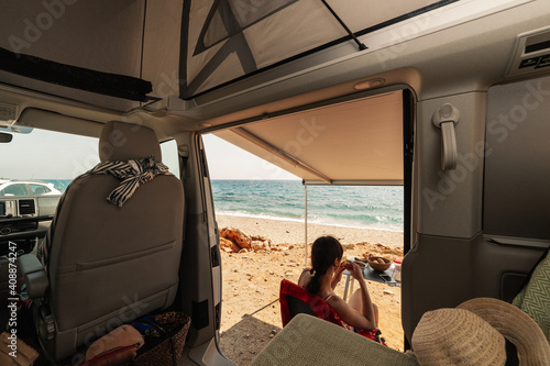 A young woman having breakfast in her caravan observing a good view of the beach