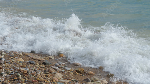 Mediterranean rocky beach with wavy sea in a cloudy morning