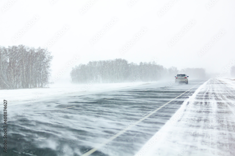 Car moves along an asphalt road during a snow storm. Car moves along an asphalt road during a snow storm.