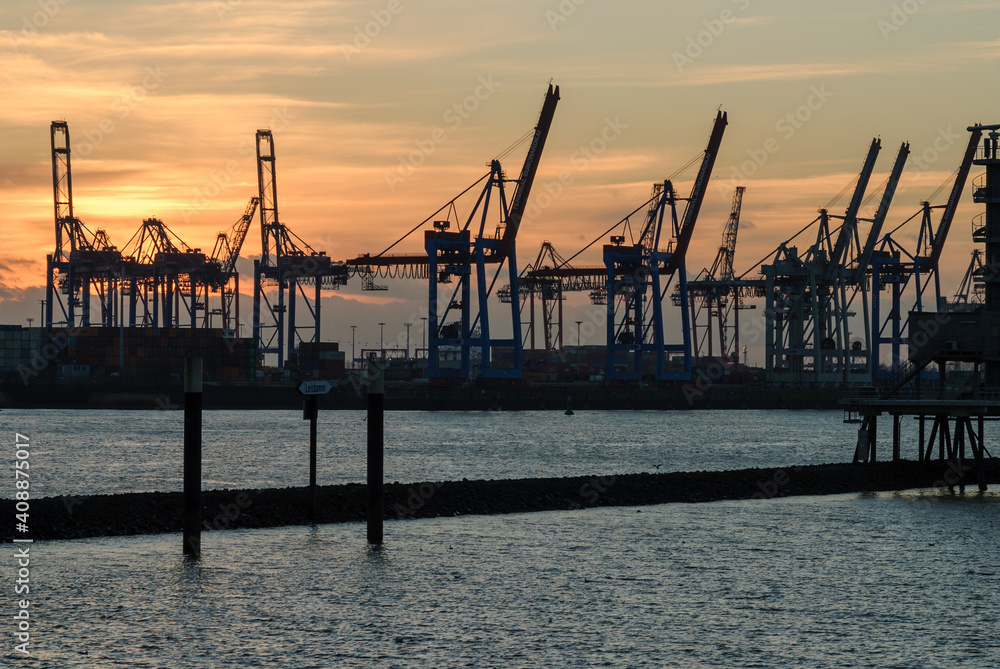 Hamburg harbor, Germany: crane silhouettes at sunset at a cloudy day