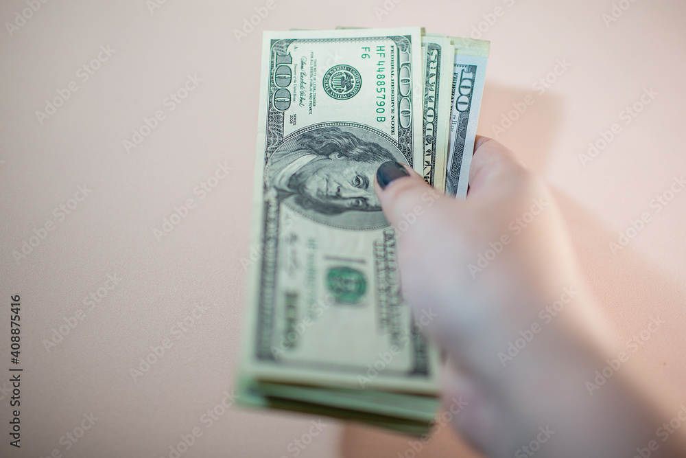 Close-up of a hand holding a pile of US banknotes. Cash of one hundred dollar bills. Close-up of a hand holding a pile of US banknotes. Cash of one hundred dollar bills.