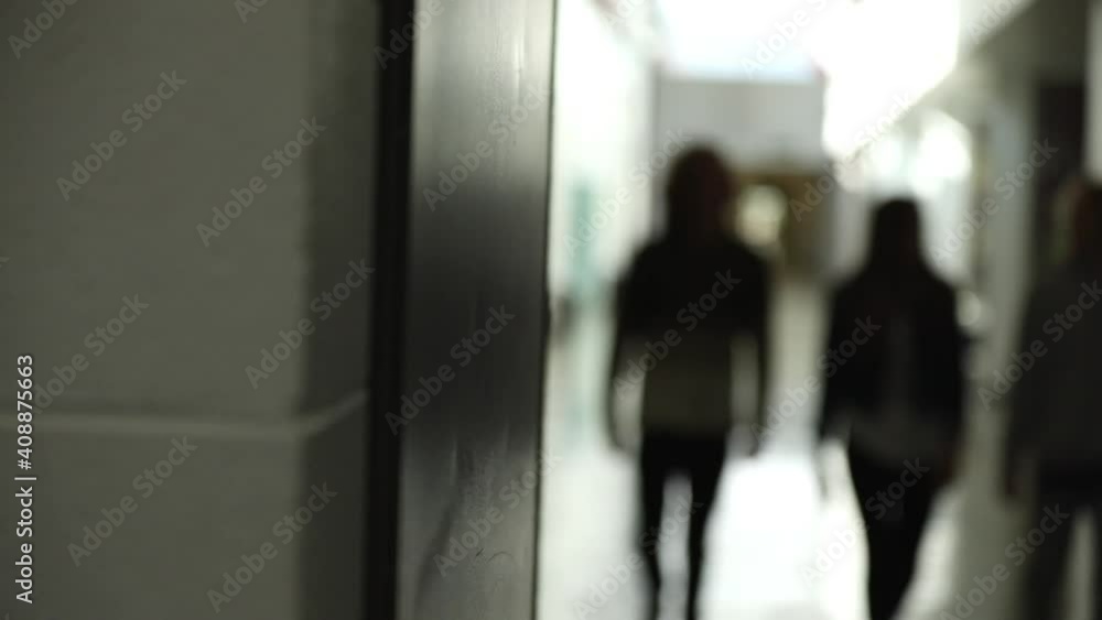 Students walking in hallway towards door in out of focus view. Students walking in hallway towards door in out of focus view.