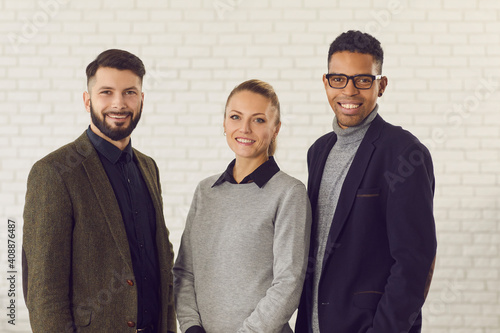 Team of positive smiling confident mixed-race co-founders of successful business startup company. Group portrait of happy young diverse coworkers, managers or business partners looking at camera