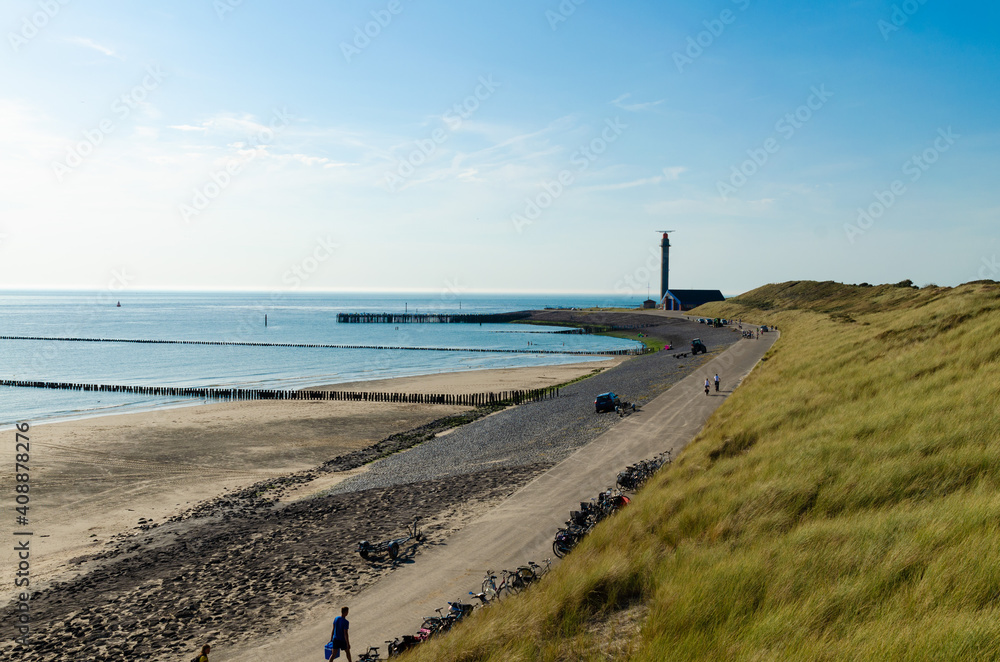 Westkapelle, Netherlands, August 2019. The beaches of this location are wide and clean: on a beautiful sunny day, the bike path along the sea has many bikes parked. The lighthouse in the background.