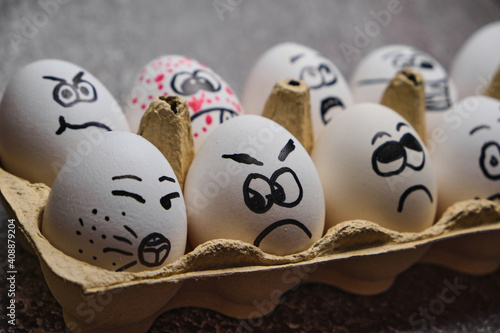 white eggs with drawn funny faces wearing medical masks at Easter holiday