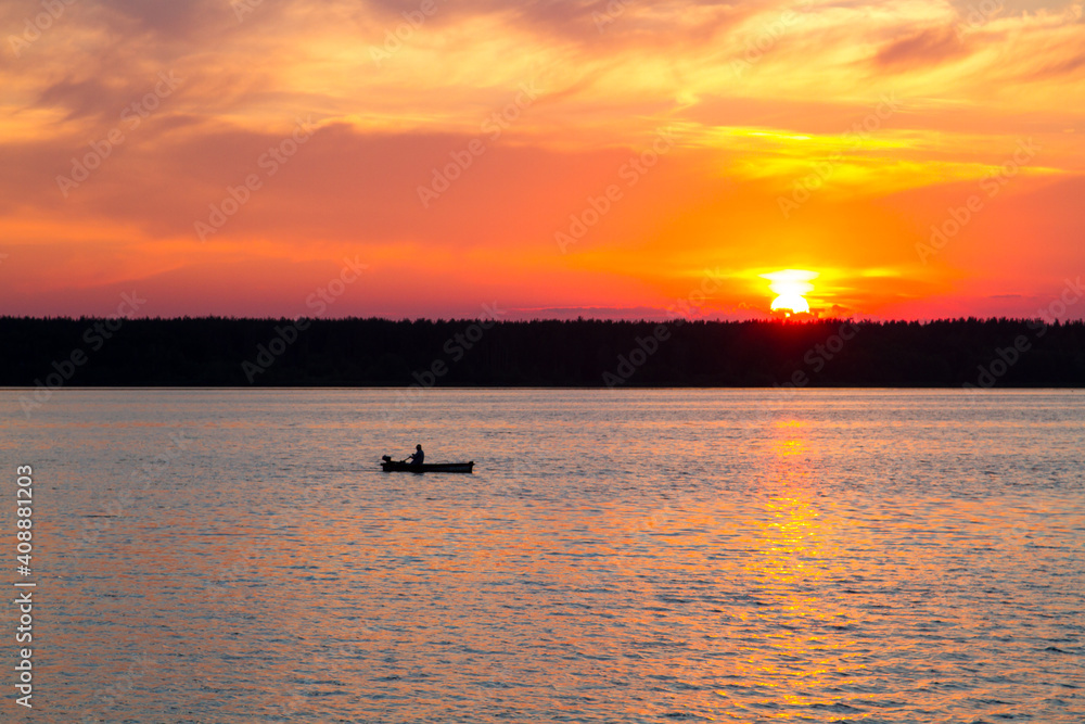 Sunset on the lake. A fisherman is fishing from a boat