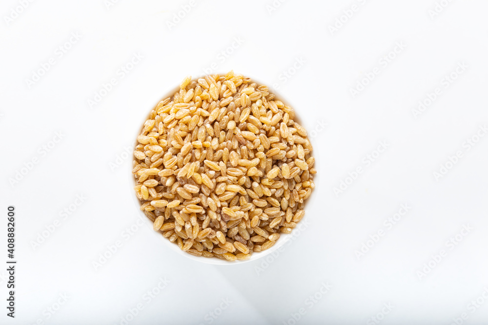 Uncooked bulgur wheat in white ceramic bowl isolated on white background.