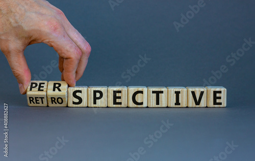 Perspective or retrospective symbol. Businessman hand turns cubes and changes word 'retrospective' to 'perspective'. Beautiful orange background. Business and perspective concept. Copy space. photo