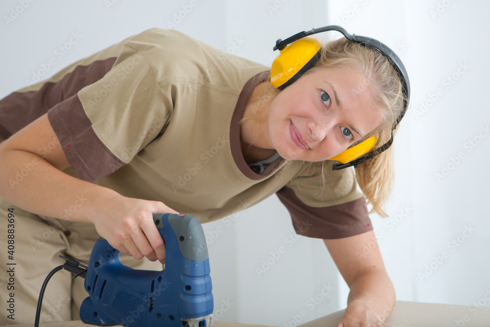 a female worker using electric jigsaw a female worker using electric jigsaw
