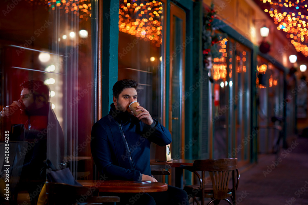 young adult man sitting alone in urban outdoor cafe on the night cozy narrow street young adult man sitting alone in urban outdoor cafe on the night cozy narrow street