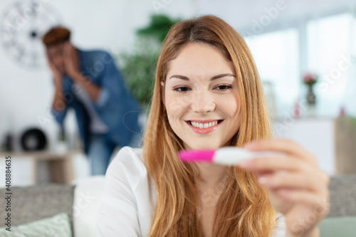 worried frustrated man and happy woman with positive pregnancy test