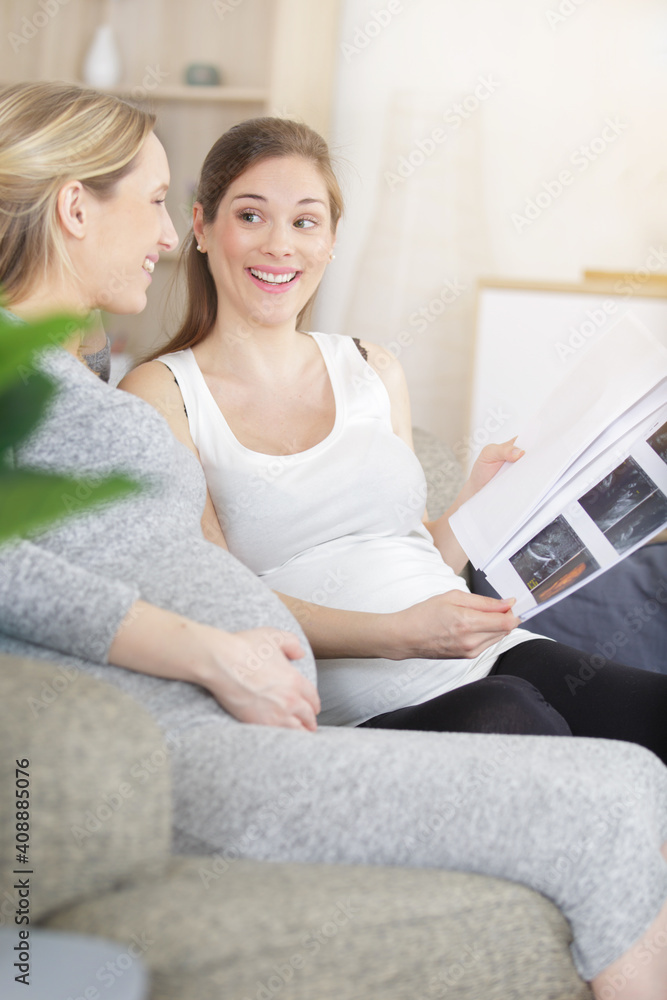 two pregnant women looking at ultrasound scans two pregnant women looking at ultrasound scans